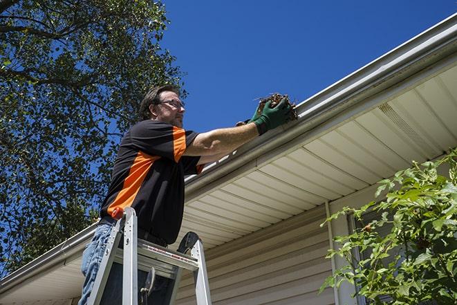 a worker using a ladder to fix a damaged gutter in Bethel Island, CA